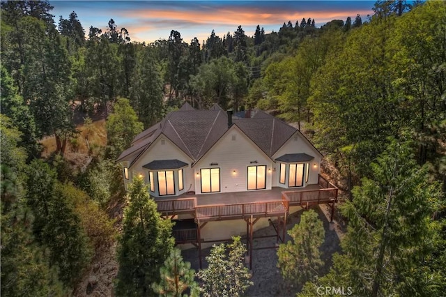 back house at dusk featuring a wooden deck