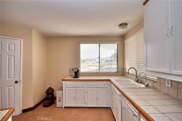 kitchen with tile counters, sink, light tile patterned floors, stainless steel dishwasher, and white cabinetry