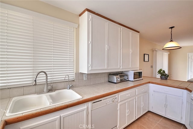 kitchen featuring white appliances, sink, tile countertops, white cabinetry, and pendant lighting