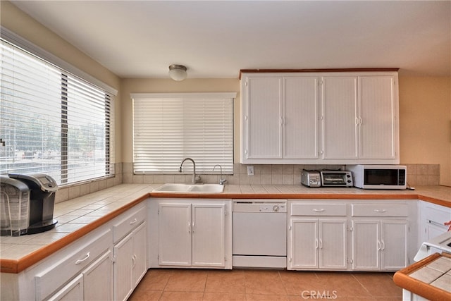 kitchen with white appliances, tile countertops, white cabinetry, and sink