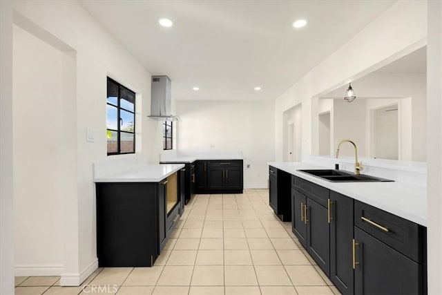 kitchen with light tile patterned floors, extractor fan, kitchen peninsula, decorative light fixtures, and sink