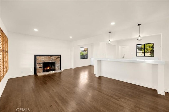 unfurnished living room featuring dark wood-type flooring, a wealth of natural light, and a fireplace