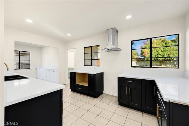 kitchen featuring wall chimney exhaust hood, sink, and light tile patterned flooring