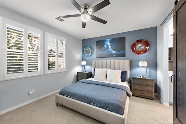 bedroom featuring a barn door, light colored carpet, and ceiling fan