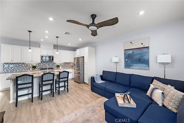 living room with ceiling fan and light hardwood / wood-style flooring