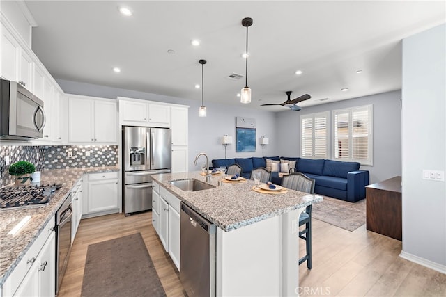 kitchen featuring stainless steel appliances, ceiling fan, a kitchen island with sink, sink, and white cabinetry