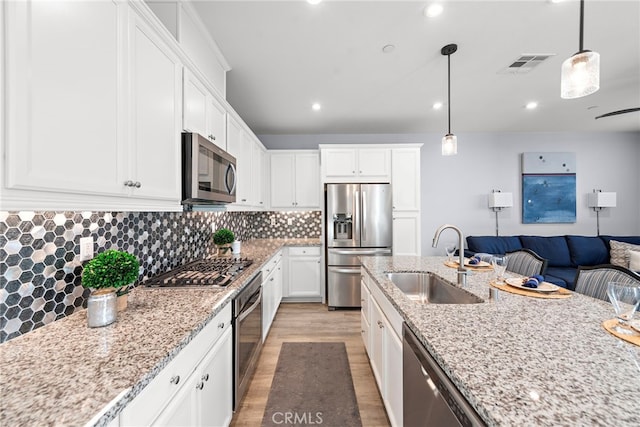 kitchen featuring light stone countertops, appliances with stainless steel finishes, light wood-type flooring, sink, and white cabinetry