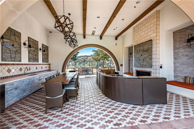 interior space featuring beamed ceiling, a towering ceiling, and a tiled fireplace