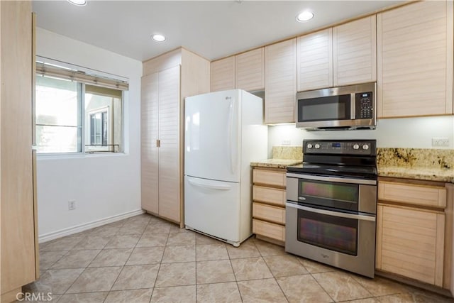 kitchen with appliances with stainless steel finishes, light brown cabinets, light stone counters, and light tile patterned flooring