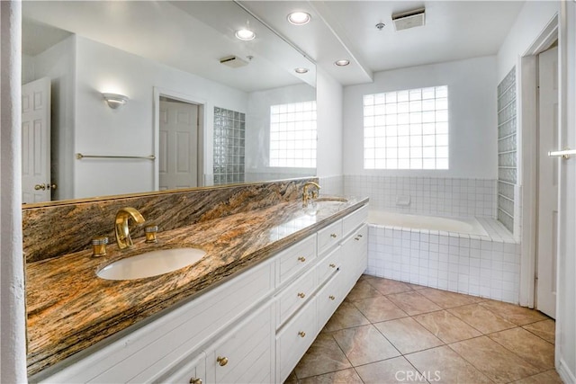 bathroom featuring tile patterned flooring, a relaxing tiled tub, and vanity