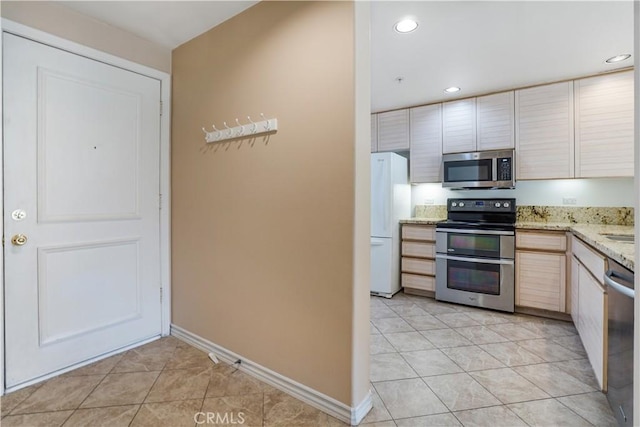 kitchen featuring light stone counters, light tile patterned flooring, and appliances with stainless steel finishes