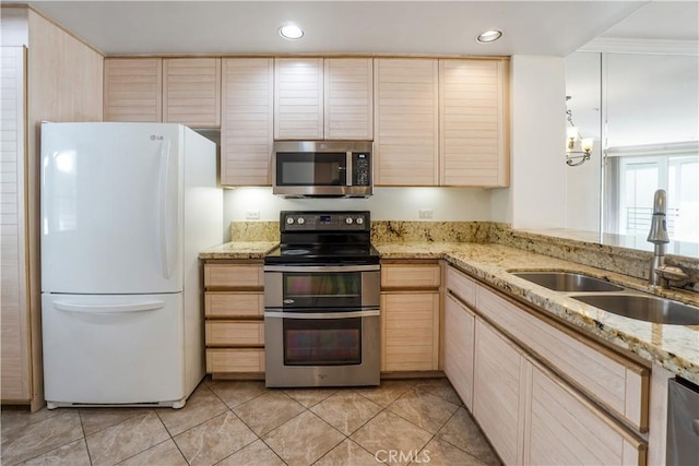 kitchen with light stone countertops, appliances with stainless steel finishes, light brown cabinetry, and sink