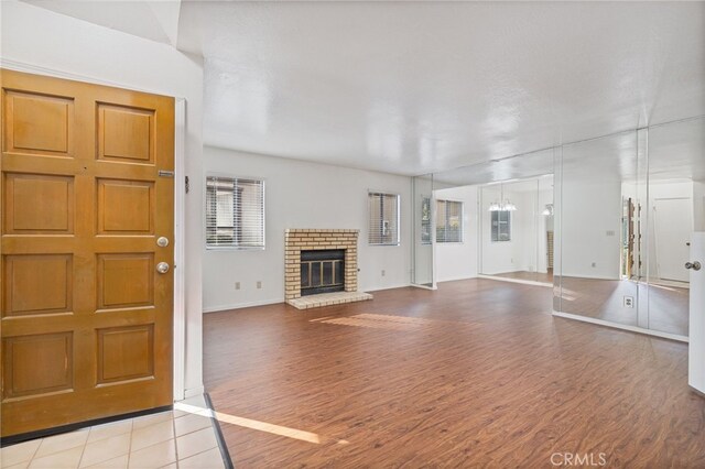 unfurnished living room featuring a brick fireplace, a textured ceiling, and light wood-type flooring