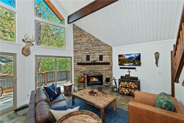 living room with beamed ceiling, a stone fireplace, and high vaulted ceiling