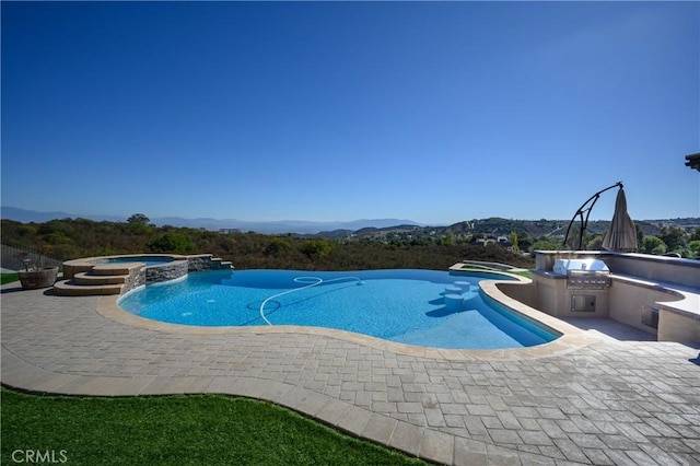 view of swimming pool with an in ground hot tub, a mountain view, a patio, and area for grilling