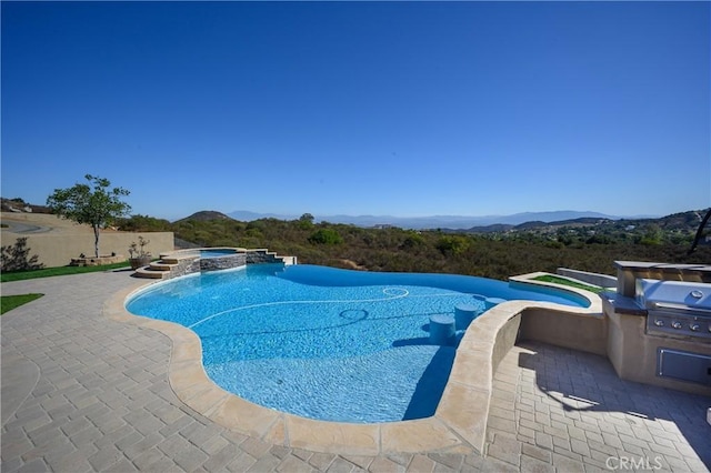 view of swimming pool with an in ground hot tub, a mountain view, and a patio