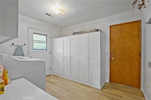 laundry area with washer / clothes dryer, a textured ceiling, and light wood-type flooring