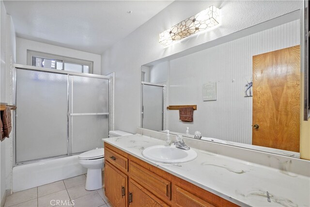 full bathroom featuring vanity, toilet, tile patterned floors, and combined bath / shower with glass door