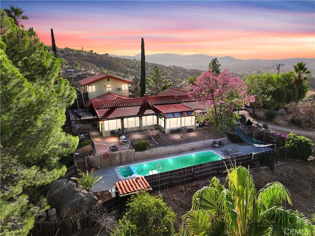 pool at dusk featuring a mountain view and a patio area