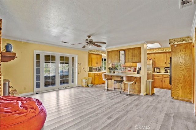 living room featuring ornamental molding, light hardwood / wood-style flooring, a textured ceiling, and ceiling fan