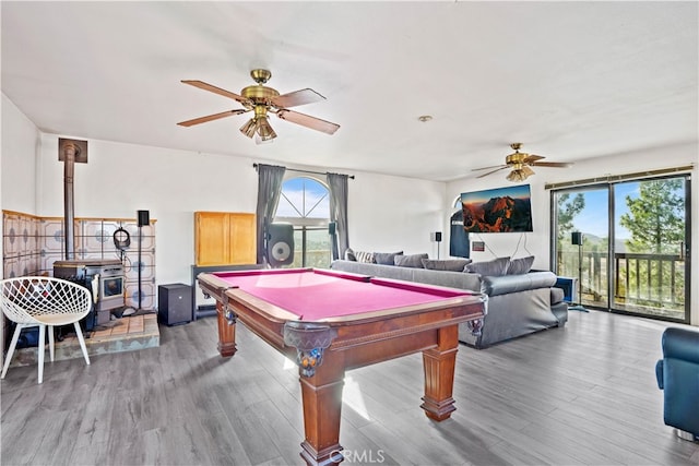 recreation room with light hardwood / wood-style floors, a wood stove, a healthy amount of sunlight, and pool table