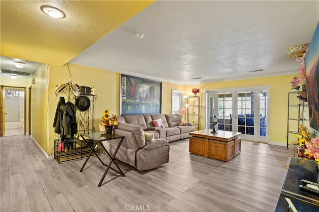 living room featuring light hardwood / wood-style floors, crown molding, and a textured ceiling