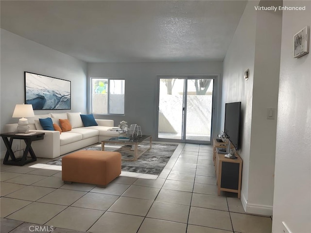 living area featuring light tile patterned floors, baseboards, and a textured ceiling