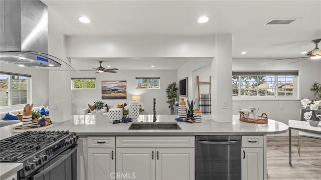 kitchen featuring white cabinets, a healthy amount of sunlight, wall chimney exhaust hood, and sink