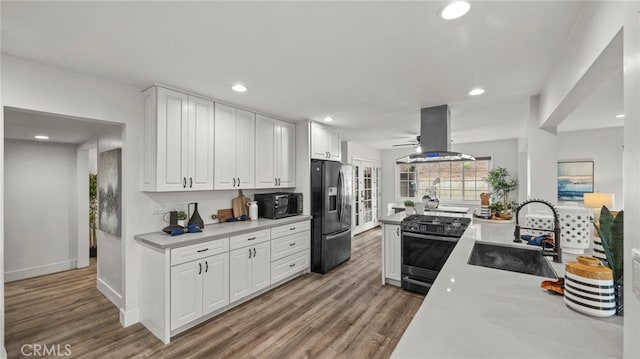 kitchen featuring white cabinets, island exhaust hood, sink, and appliances with stainless steel finishes