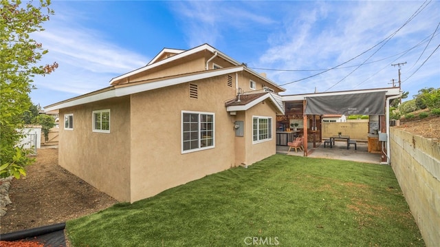 rear view of property featuring a lawn and a patio area