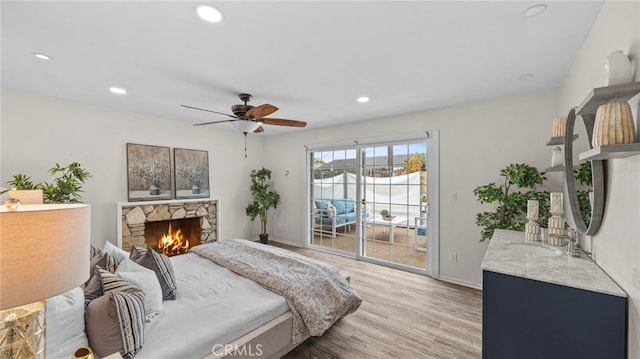 bedroom with access to outside, sink, light hardwood / wood-style flooring, ceiling fan, and a fireplace