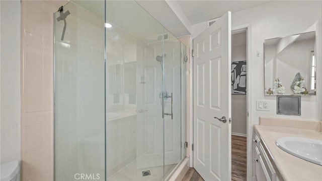 bathroom with hardwood / wood-style floors, vanity, and walk in shower