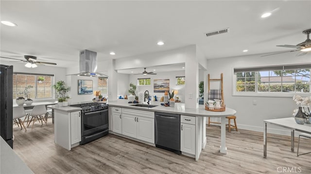 kitchen featuring white cabinetry, dishwasher, black range with gas stovetop, kitchen peninsula, and island exhaust hood