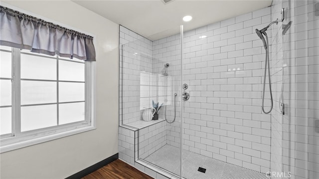 bathroom featuring a healthy amount of sunlight, wood-type flooring, and walk in shower