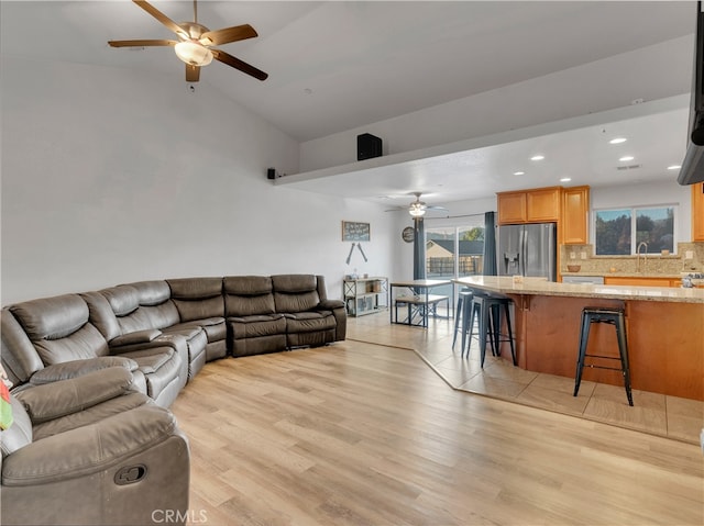 living room featuring sink, vaulted ceiling, light wood-type flooring, and ceiling fan