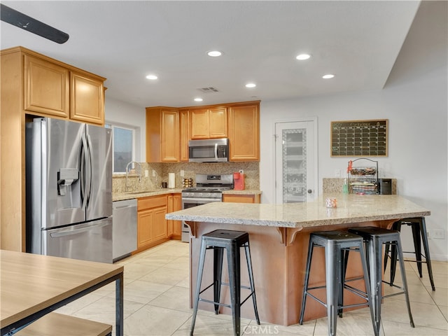 kitchen featuring appliances with stainless steel finishes, light stone countertops, sink, and a kitchen breakfast bar