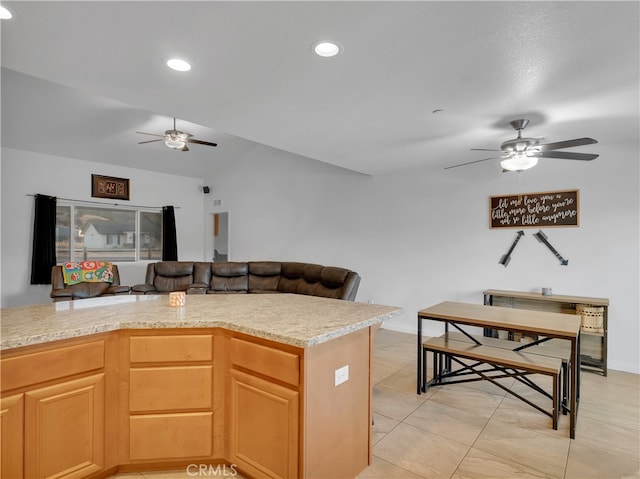 kitchen with ceiling fan, light tile patterned flooring, light stone countertops, and vaulted ceiling