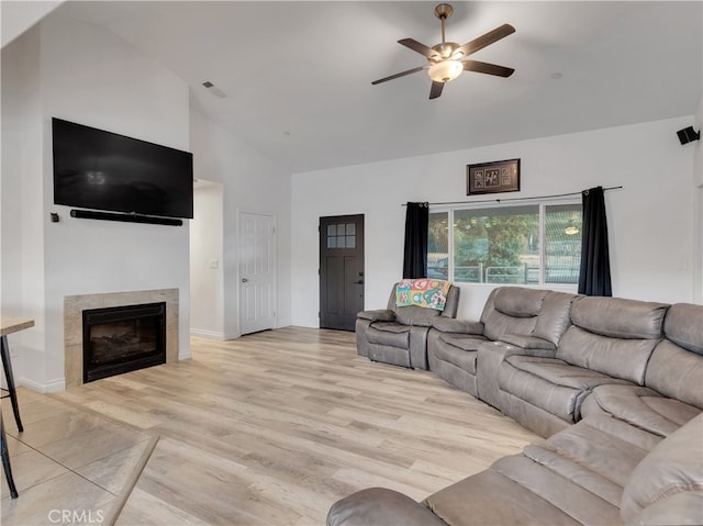 living room featuring light hardwood / wood-style flooring, a fireplace, high vaulted ceiling, and ceiling fan