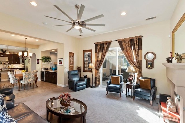 carpeted living room with ceiling fan with notable chandelier