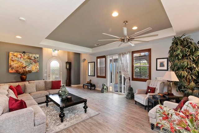 living room featuring a tray ceiling, ceiling fan, and light hardwood / wood-style floors