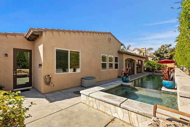 back of house featuring a patio and a pool with hot tub