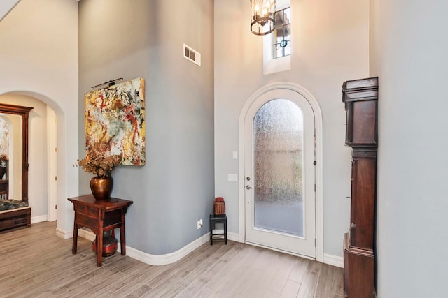 foyer entrance featuring a notable chandelier, a high ceiling, and light hardwood / wood-style flooring