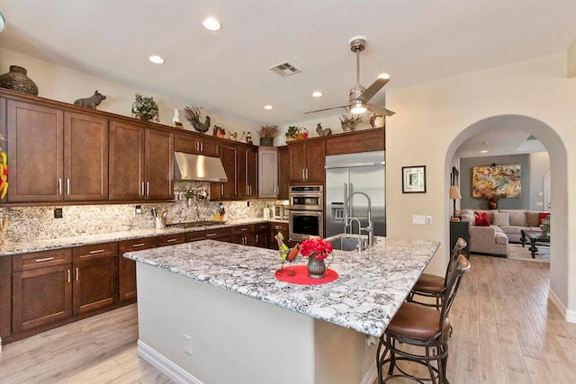 kitchen with a center island with sink, appliances with stainless steel finishes, and light hardwood / wood-style flooring