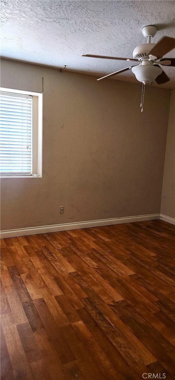 unfurnished room with a textured ceiling and dark wood-type flooring