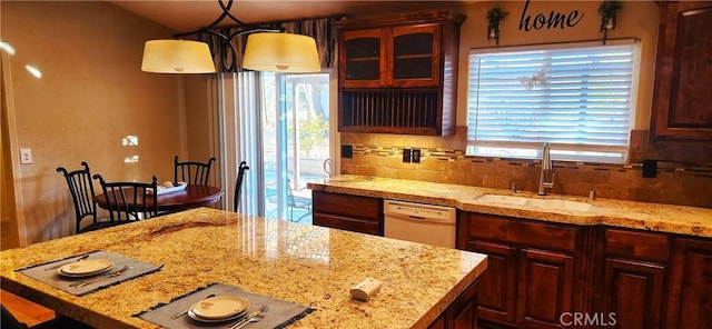 kitchen with decorative backsplash, light stone countertops, white dishwasher, sink, and decorative light fixtures