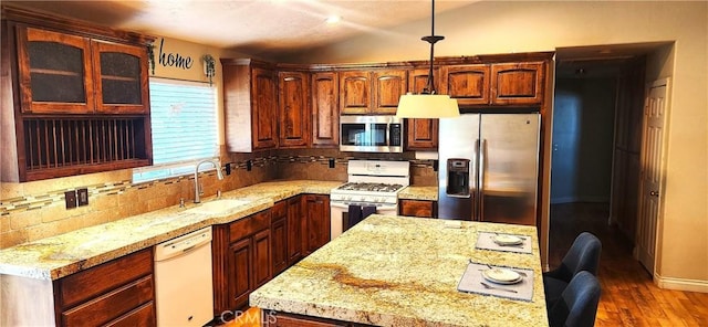 kitchen featuring sink, hanging light fixtures, dark hardwood / wood-style flooring, decorative backsplash, and appliances with stainless steel finishes