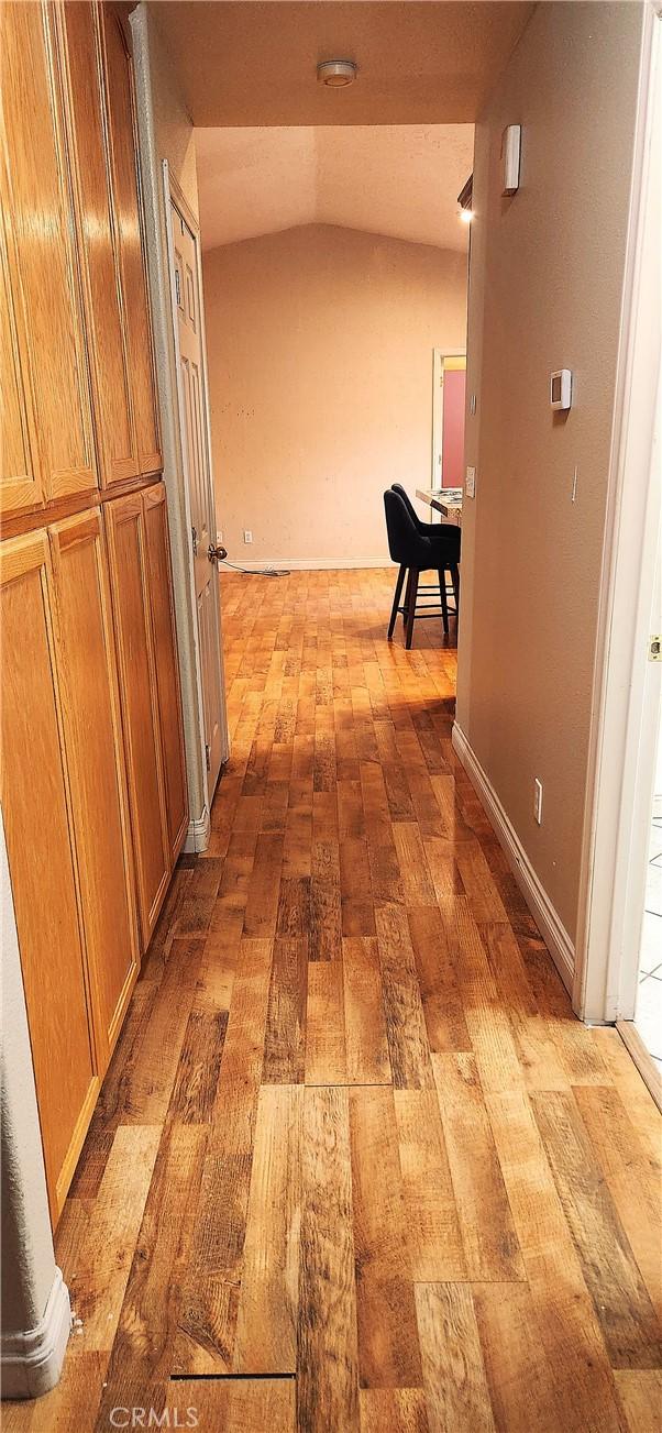 corridor with hardwood / wood-style flooring and lofted ceiling