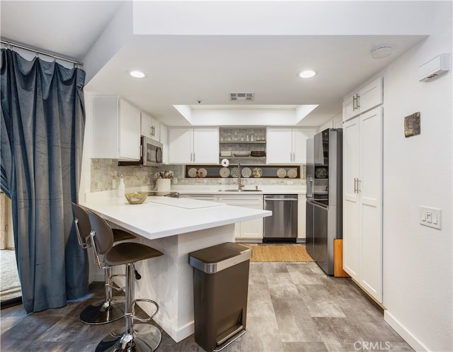 kitchen featuring backsplash, white cabinetry, light hardwood / wood-style flooring, sink, and stainless steel appliances