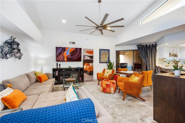 living room with ceiling fan, high vaulted ceiling, and a fireplace