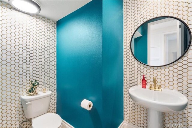 bathroom with sink, toilet, and tasteful backsplash